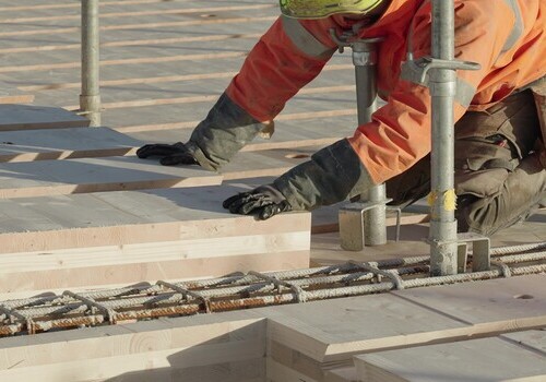 Un ouvrier pose le plancher mixte bois béton HOBOA
