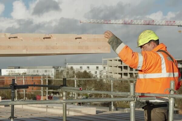 Un ouvrier en train de construire avec le plancher bas-carbone HOBOA